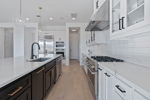 kitchen featuring white cabinetry, decorative light fixtures, light stone counters, and premium appliances