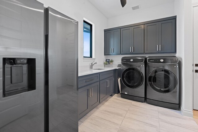 clothes washing area with sink, washer and clothes dryer, and cabinets