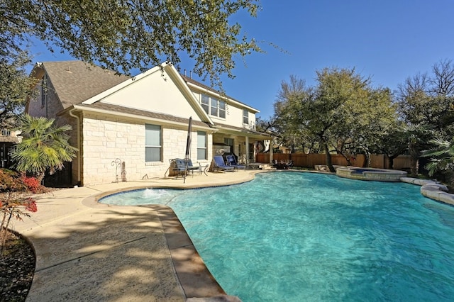 12304 Aralia Ridge Dr, Austin, TX 78739 - rear view of house featuring a patio, a fenced backyard, roof with shingles, a pool with connected hot tub, and stone siding