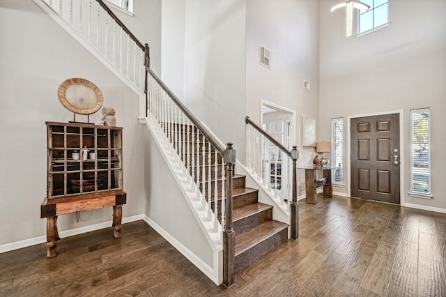 foyer entrance featuring dark wood-type flooring and a towering ceiling