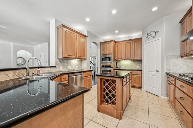 kitchen with dark stone countertops, stainless steel appliances, sink, and light tile patterned floors