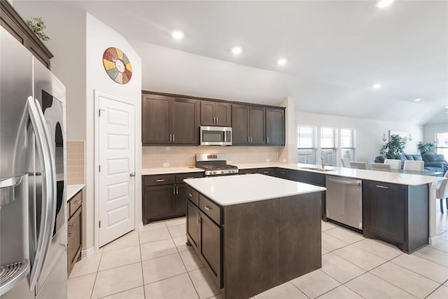 kitchen with light tile patterned floors, backsplash, dark brown cabinets, stainless steel appliances, and a center island