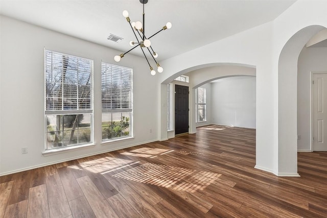 unfurnished dining area featuring a healthy amount of sunlight, wood finished floors, a chandelier, and visible vents