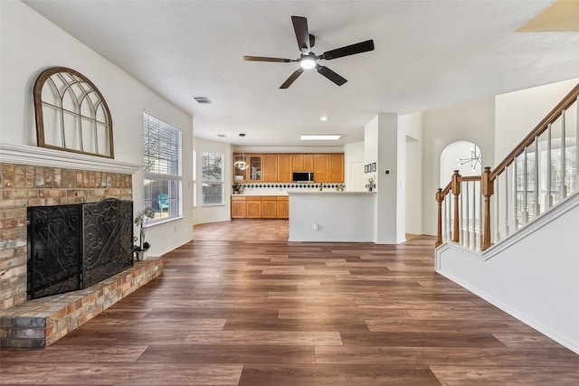 unfurnished living room featuring ceiling fan, a fireplace, and dark hardwood / wood-style flooring