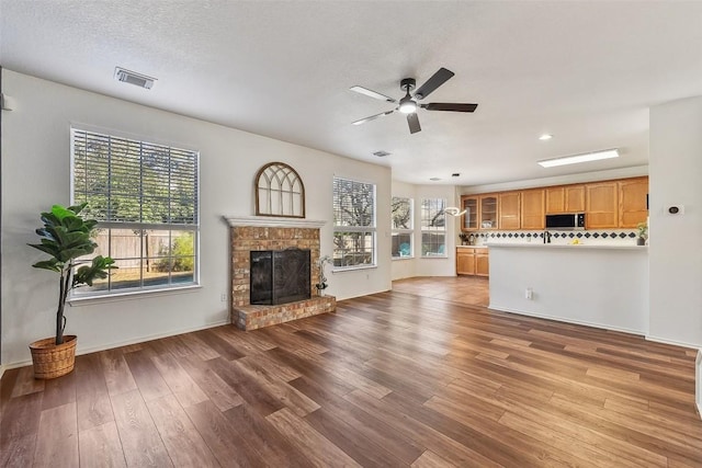 unfurnished living room with ceiling fan, plenty of natural light, a fireplace, and light hardwood / wood-style floors