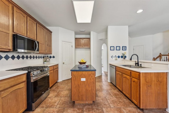 kitchen with arched walkways, a sink, backsplash, a kitchen island, and appliances with stainless steel finishes