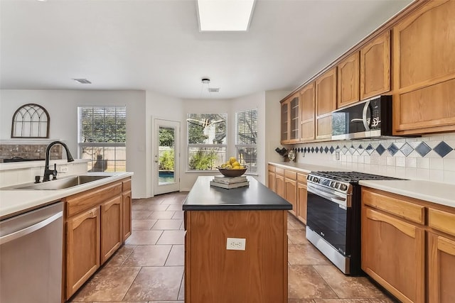 kitchen featuring appliances with stainless steel finishes, a kitchen island, a sink, and decorative backsplash