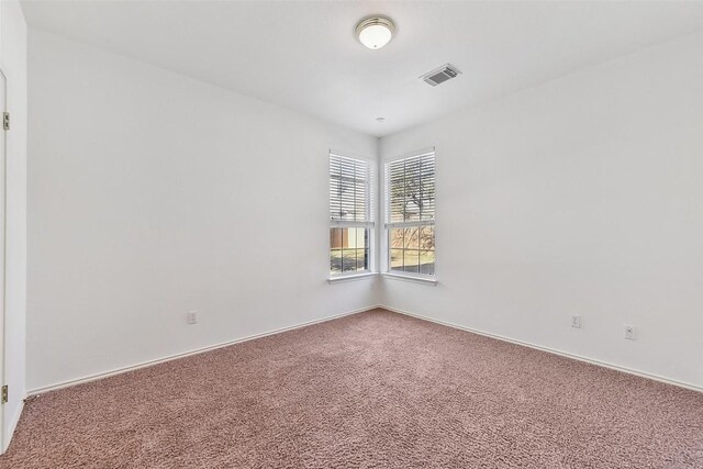 carpeted spare room featuring baseboards and visible vents
