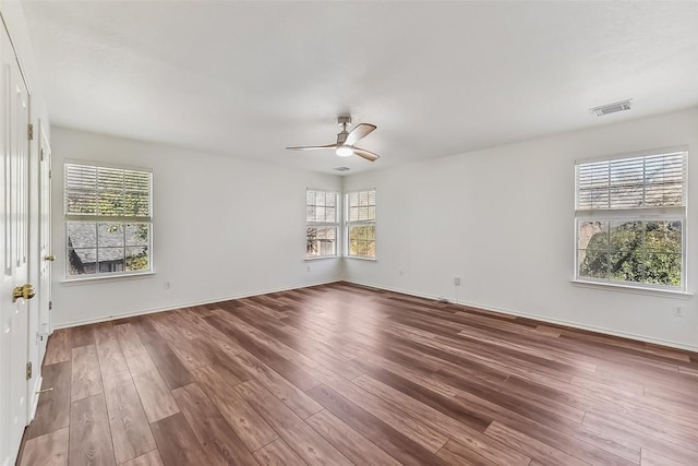 unfurnished room with baseboards, wood finished floors, visible vents, and a ceiling fan