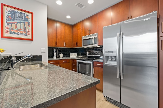 360 Nueces St Unit 914, Austin, TX 78701 - kitchen with appliances with stainless steel finishes, a sink, tasteful backsplash, brown cabinets, and recessed lighting