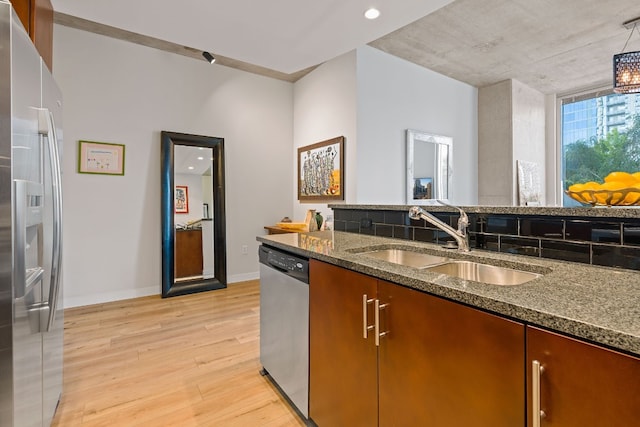 360 Nueces St Unit 914, Austin, TX 78701 - kitchen with stainless steel appliances, a sink, light wood-style flooring, dark stone counters, and baseboards