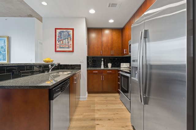 360 Nueces St Unit 914, Austin, TX 78701 - kitchen featuring stainless steel appliances, light wood-style floors, a sink, a peninsula, and dark stone counters
