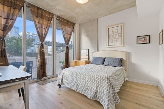 360 Nueces St Unit 914, Austin, TX 78701 - bedroom with access to exterior, hardwood / wood-style flooring, a wall of windows, and baseboards