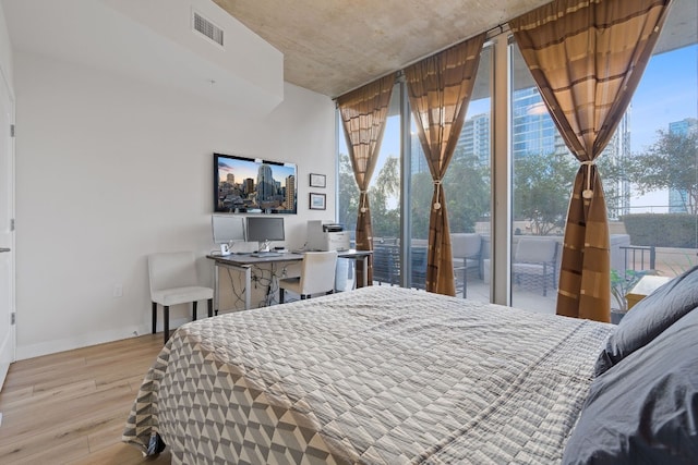 360 Nueces St Unit 914, Austin, TX 78701 - bedroom featuring light wood-style floors, baseboards, access to exterior, a desk, and floor to ceiling windows