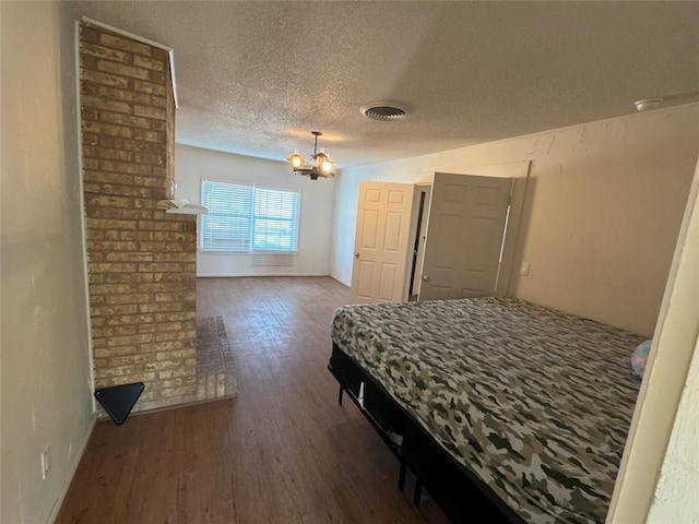 bedroom with an inviting chandelier, dark hardwood / wood-style flooring, and a textured ceiling