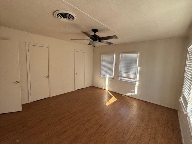 unfurnished bedroom featuring dark hardwood / wood-style flooring, a textured ceiling, and ceiling fan