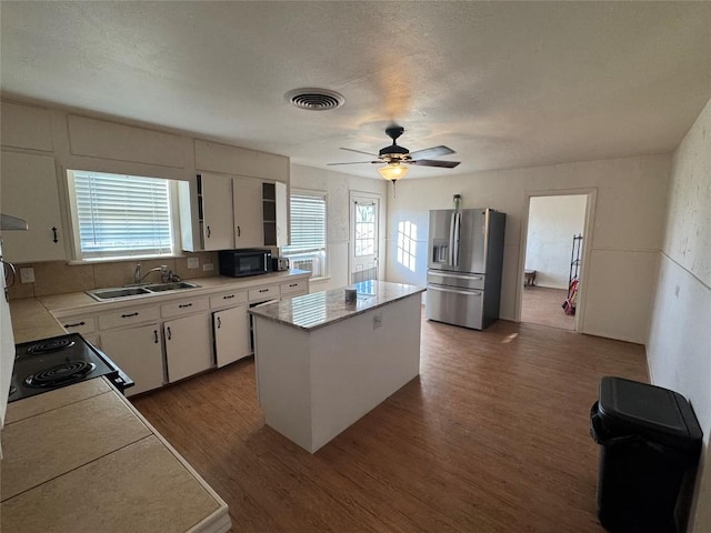 kitchen featuring dark wood-type flooring, stainless steel fridge, a center island, and white cabinets