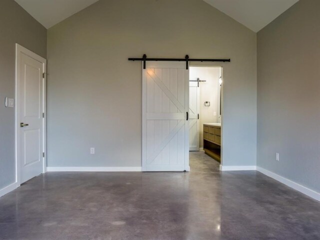 spare room with high vaulted ceiling and a barn door