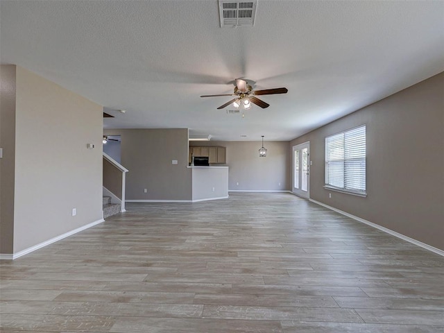 unfurnished living room with a textured ceiling, ceiling fan, and light hardwood / wood-style floors