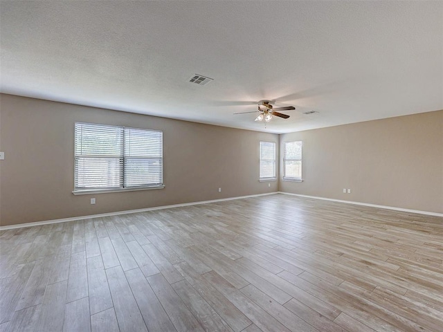 spare room with a textured ceiling, light hardwood / wood-style floors, and ceiling fan