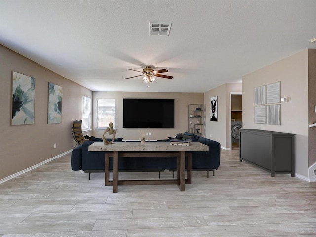 living room featuring washer / clothes dryer, ceiling fan, a textured ceiling, and light hardwood / wood-style floors