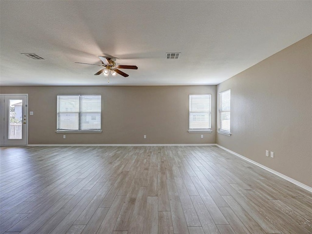 empty room with ceiling fan, light hardwood / wood-style flooring, and a textured ceiling