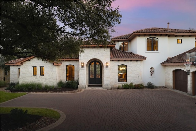 mediterranean / spanish house with a garage and french doors