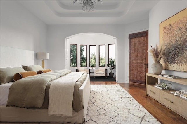 bedroom featuring dark hardwood / wood-style floors, ceiling fan, and a tray ceiling