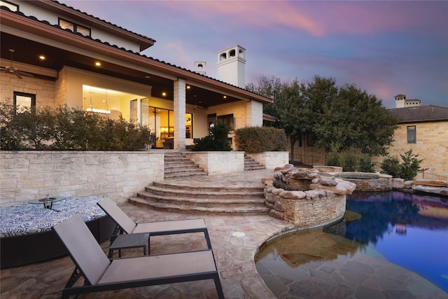 pool at dusk with an in ground hot tub, ceiling fan, and a patio