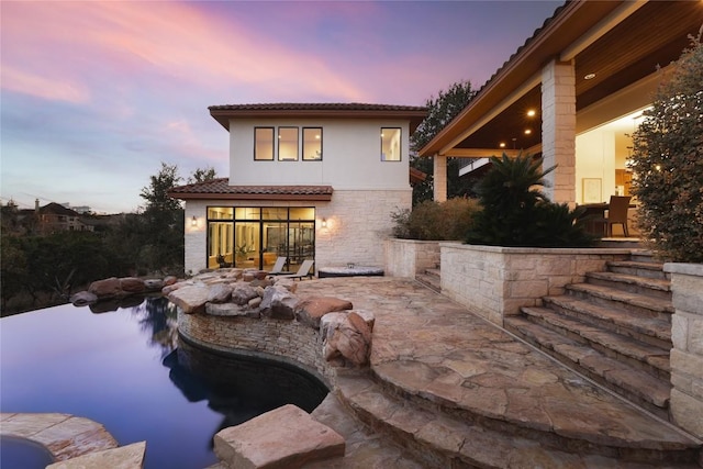 pool at dusk featuring a patio area