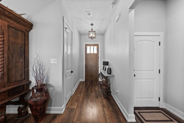 foyer with dark wood-type flooring and an inviting chandelier