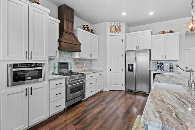 kitchen with sink, white cabinetry, stainless steel appliances, decorative light fixtures, and custom exhaust hood