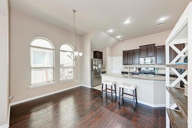 kitchen featuring appliances with stainless steel finishes, dark brown cabinetry, tasteful backsplash, decorative light fixtures, and a chandelier