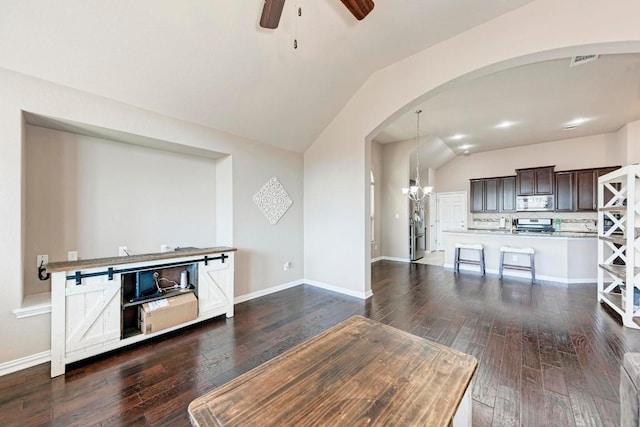 unfurnished living room with lofted ceiling, dark hardwood / wood-style flooring, and ceiling fan with notable chandelier