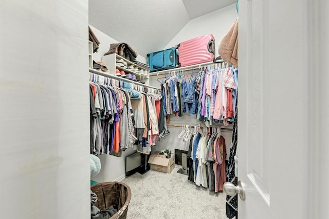 walk in closet with vaulted ceiling and carpet flooring