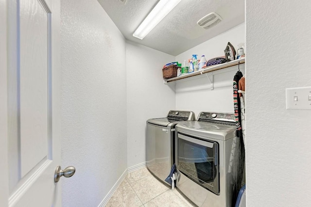 washroom with separate washer and dryer, light tile patterned floors, and a textured ceiling