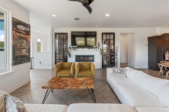 living room with a wealth of natural light, visible vents, a glass covered fireplace, and recessed lighting