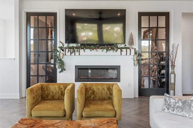 living room with a glass covered fireplace and baseboards