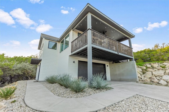 view of front facade with concrete driveway, an attached garage, and a balcony