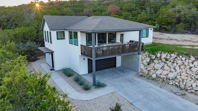 view of front of home featuring a garage, concrete driveway, and roof with shingles