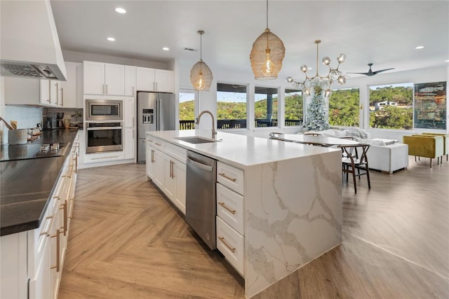 kitchen featuring stainless steel appliances, a spacious island, a sink, white cabinetry, and range hood