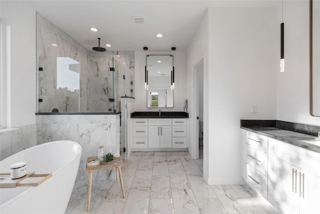 full bath featuring a stall shower, marble finish floor, vanity, a freestanding tub, and recessed lighting