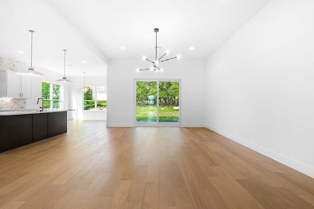 unfurnished living room with a chandelier and light hardwood / wood-style floors