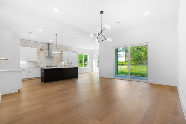 unfurnished living room with sink, light hardwood / wood-style flooring, and a notable chandelier