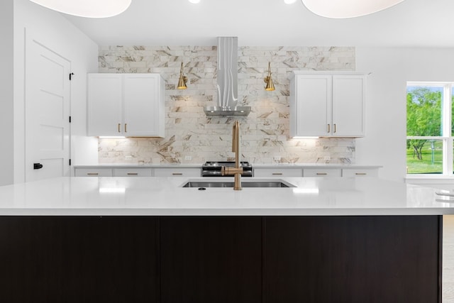 kitchen featuring a kitchen island with sink, wall chimney range hood, white cabinets, and backsplash