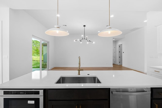 kitchen featuring stainless steel appliances, sink, a kitchen island with sink, and decorative light fixtures