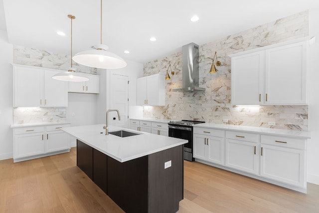 kitchen with sink, stainless steel range with electric cooktop, hanging light fixtures, wall chimney range hood, and white cabinets