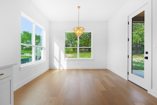 unfurnished dining area featuring an inviting chandelier, light hardwood / wood-style flooring, and a healthy amount of sunlight