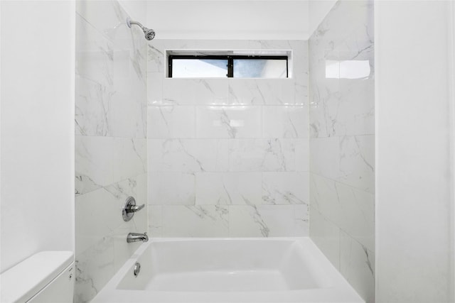 bathroom with tiled shower / bath combo and toilet