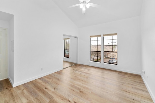 empty room with ceiling fan, high vaulted ceiling, and light wood-type flooring